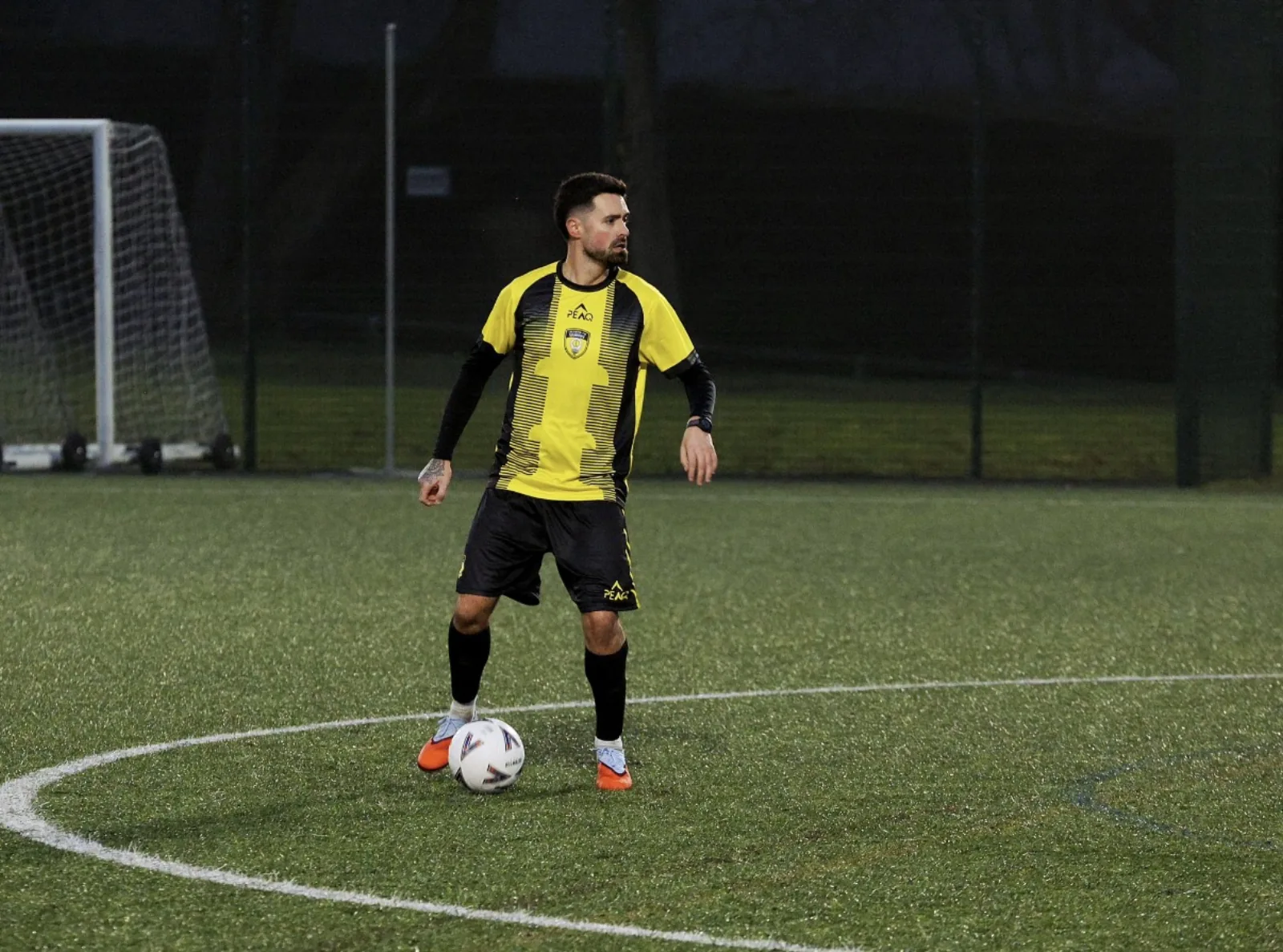 Player wearing a yellow Peaq custom football kit on the pitch.