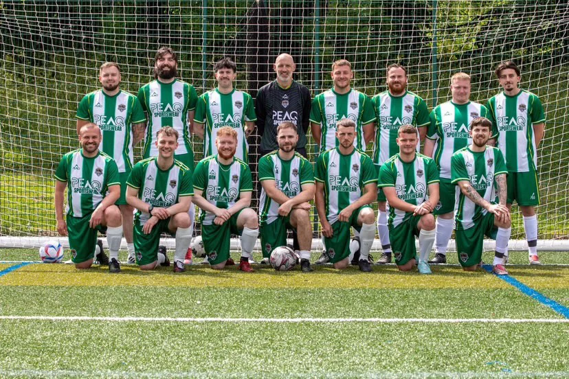 Football team in green and white custom Peaq kit, lined up on the pitch.